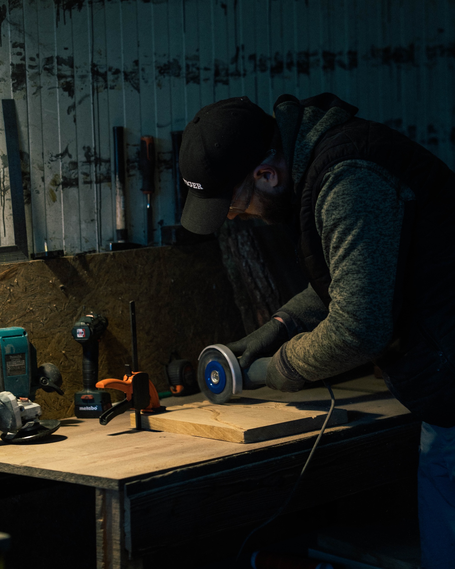 Craftsman shaping a slab of oak with an angle grinder on the workshop bench